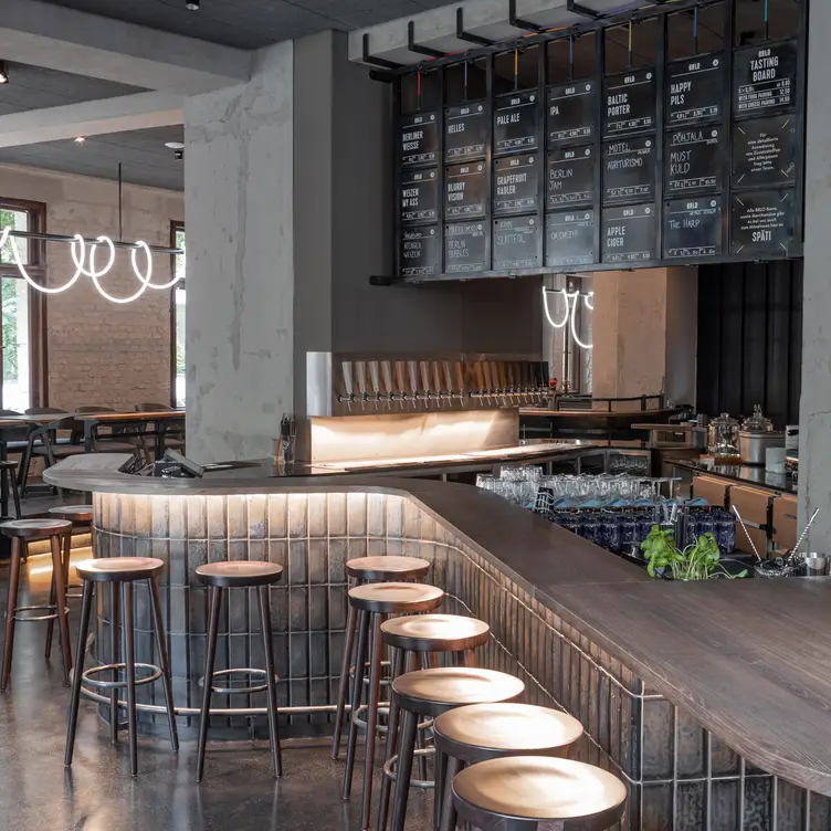 Geschwungener Tresen und moderne Einrichtung mit unverputzten Betonwänden im BRŁO, einem der besten deutschen Restaurants in Berlin