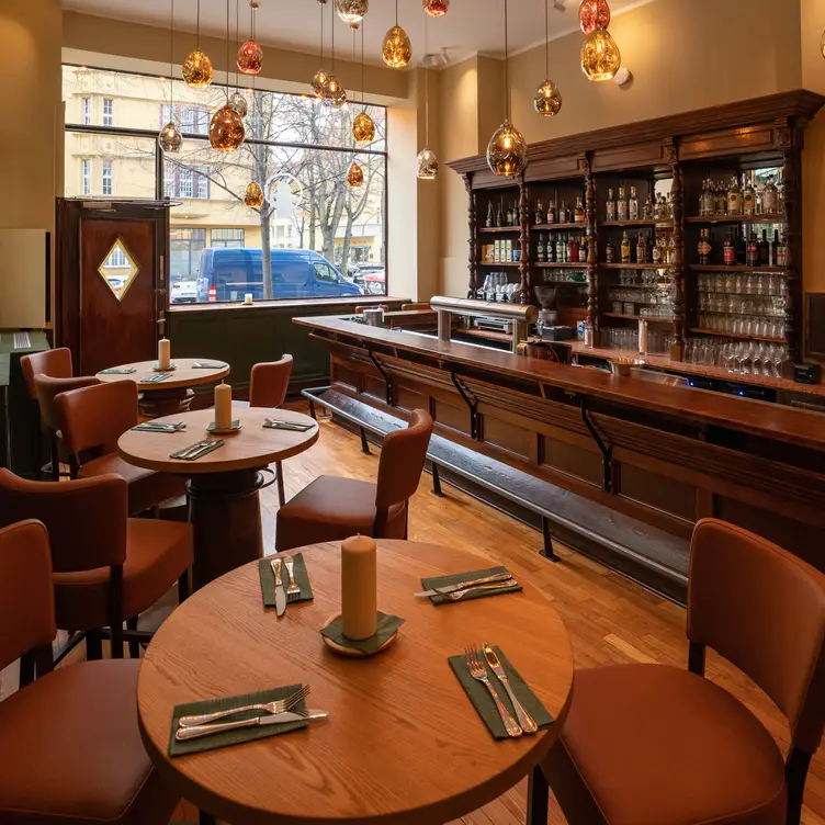 Gutbürgerliches Ambiente in gedeckten Brauntönen mit Tischen und eichenbrauner Holztheke in der Schnitzelei, einem der besten deutschen Restaurants in Berlin