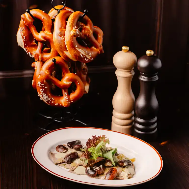 Teller mit kleiner Vorspeise und Brezen am Haken beim Haxengrill, einem der besten Restaurants in Münchens Innenstadt.
