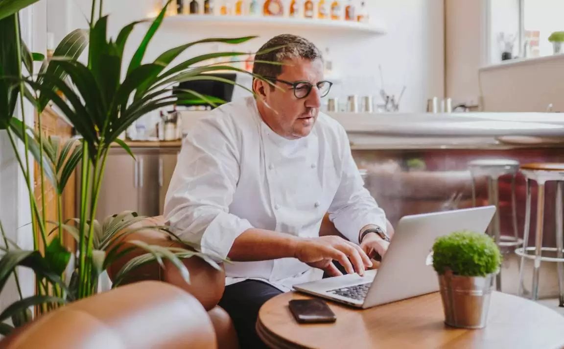 Restaurantbesitzer arbeitet mit einem Laptop